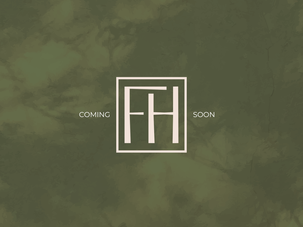 Aerial view of a vacant grassy lot outlined in red, surrounded by houses and greenery near a road.