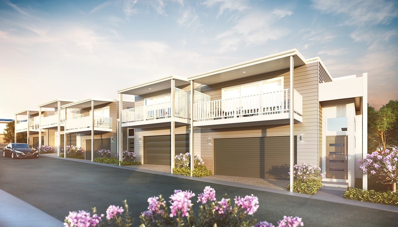 Row of modern townhouses with balconies, garages, and landscaped front yards; daytime.