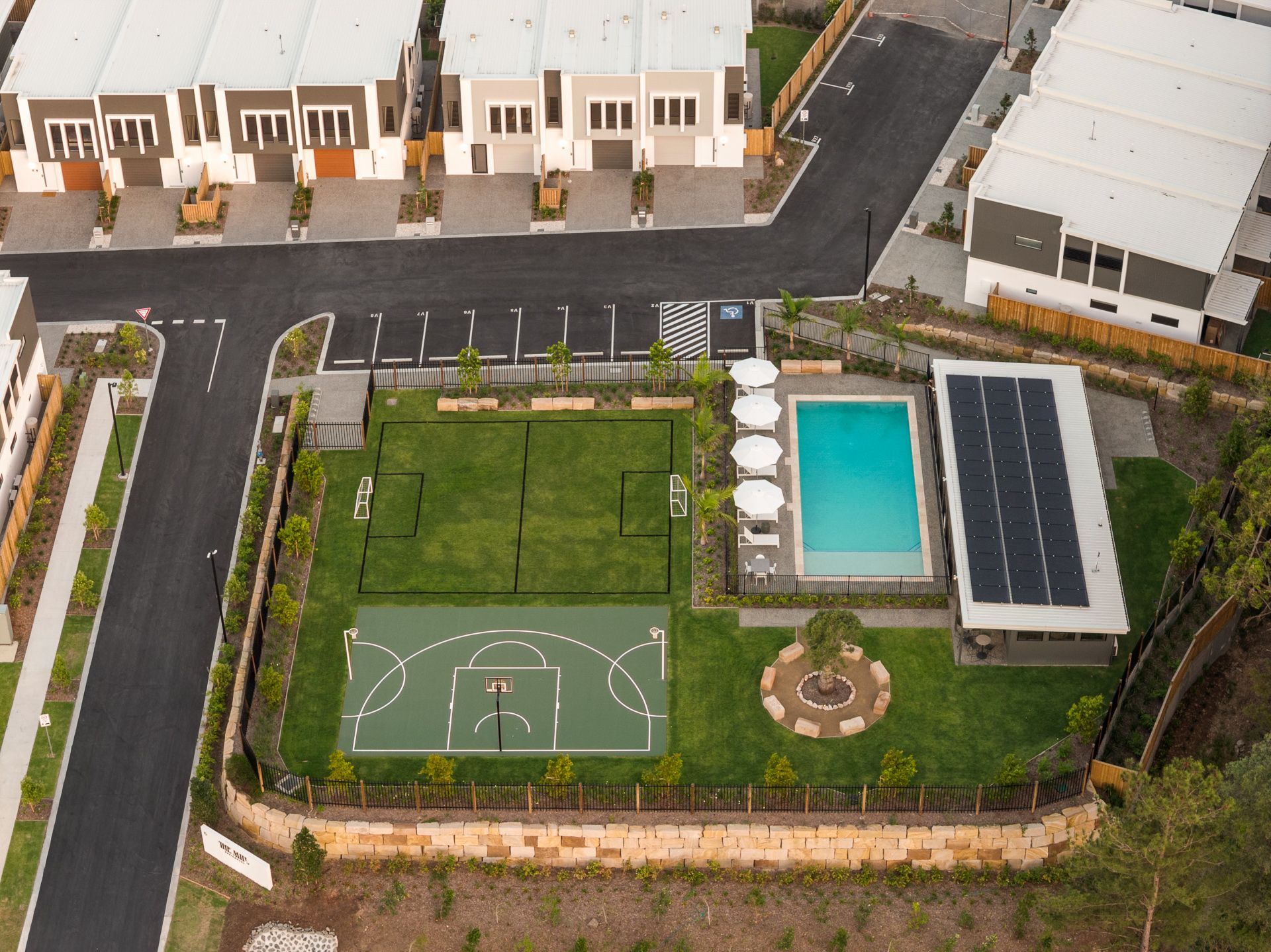 Aerial view of a community area with a pool, sports court, and residential buildings.