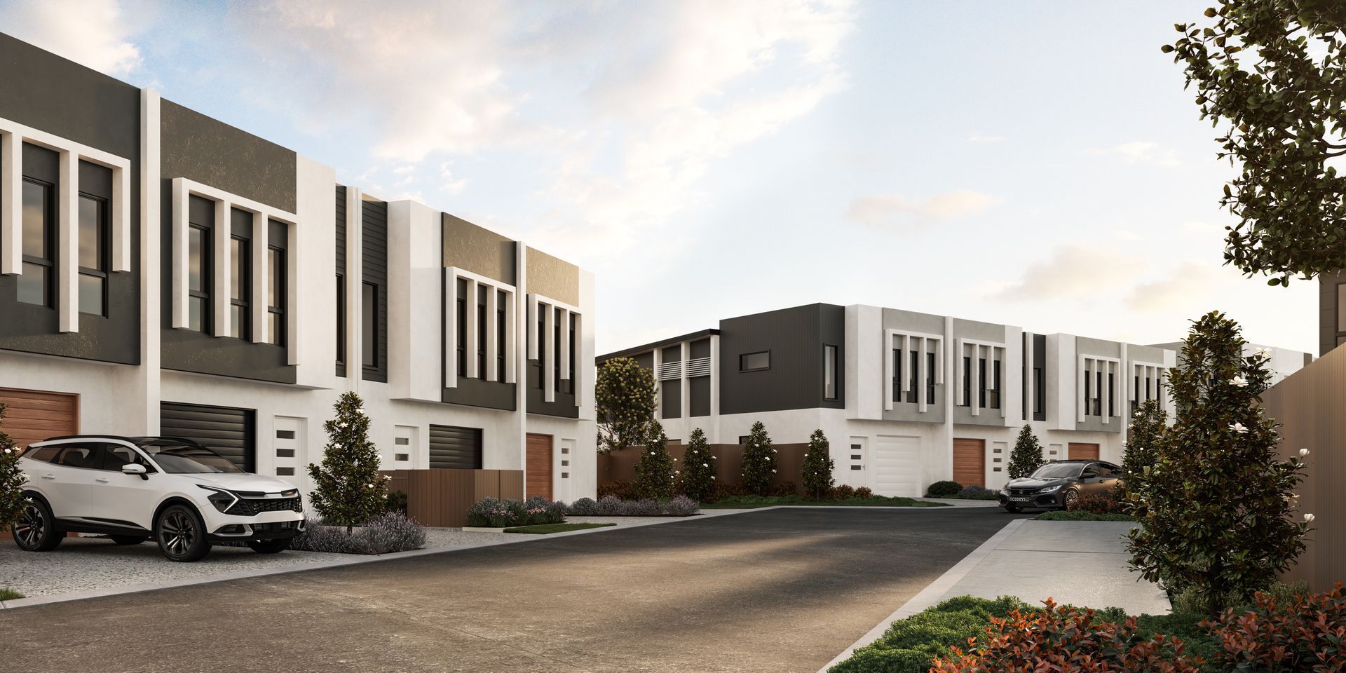 Modern townhouses with cars parked on a paved street.