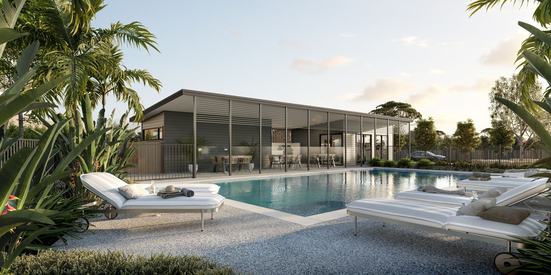 Swimming pool with lounge chairs, building with a covered outdoor area, and palm trees.