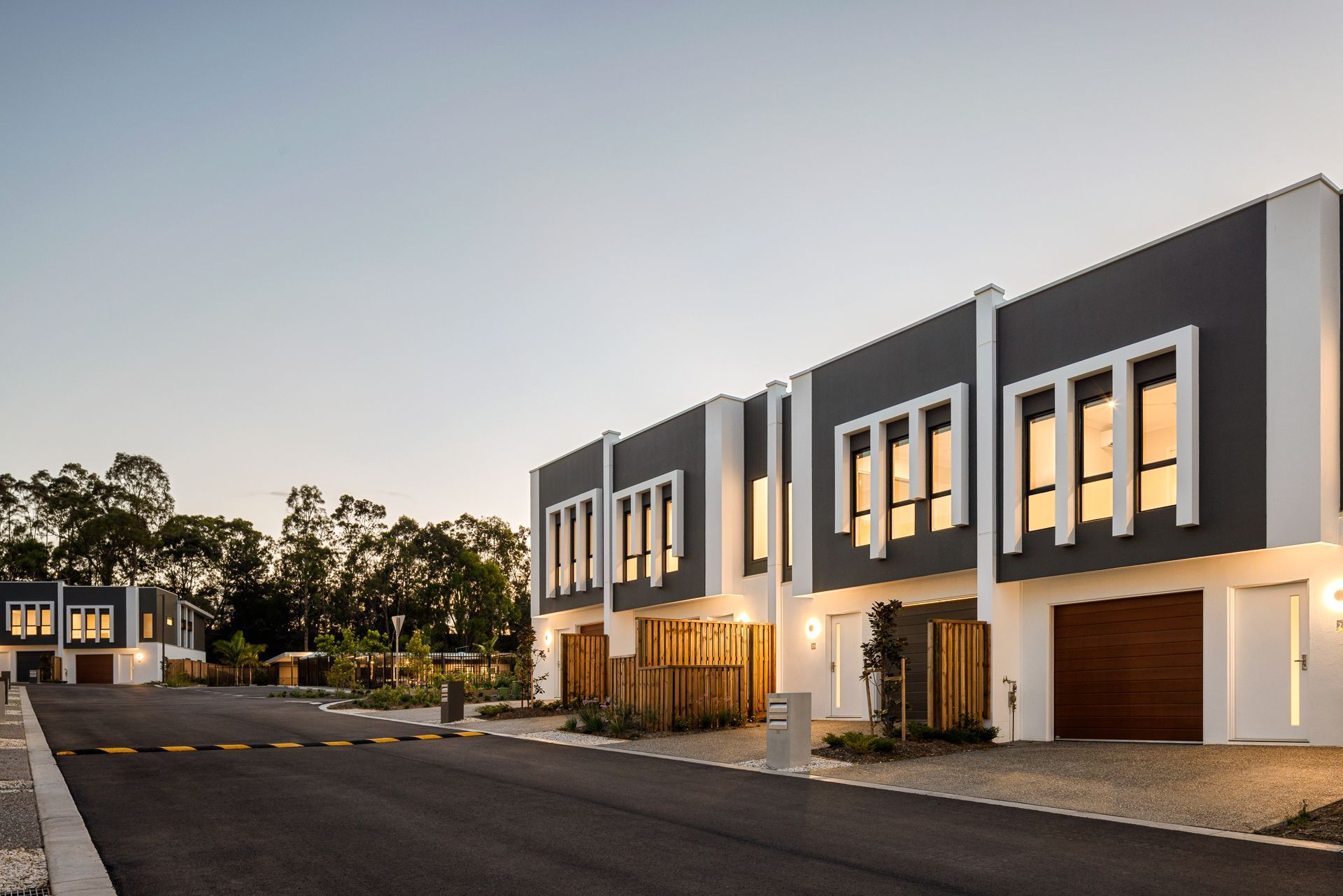 Row of modern townhouses with gray and white exteriors, at dusk.