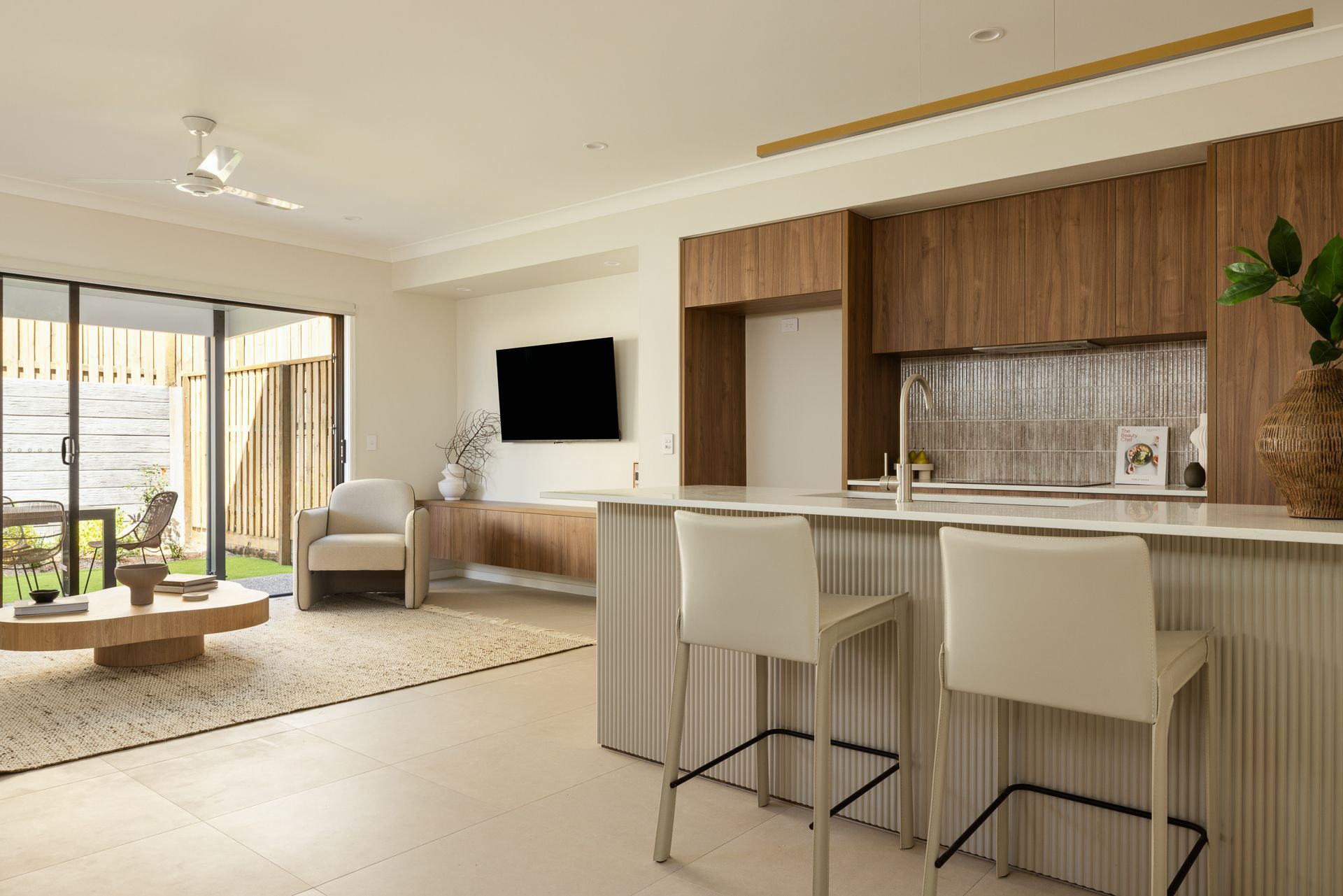 Modern kitchen and living room with a bar, TV, and outdoor access.
