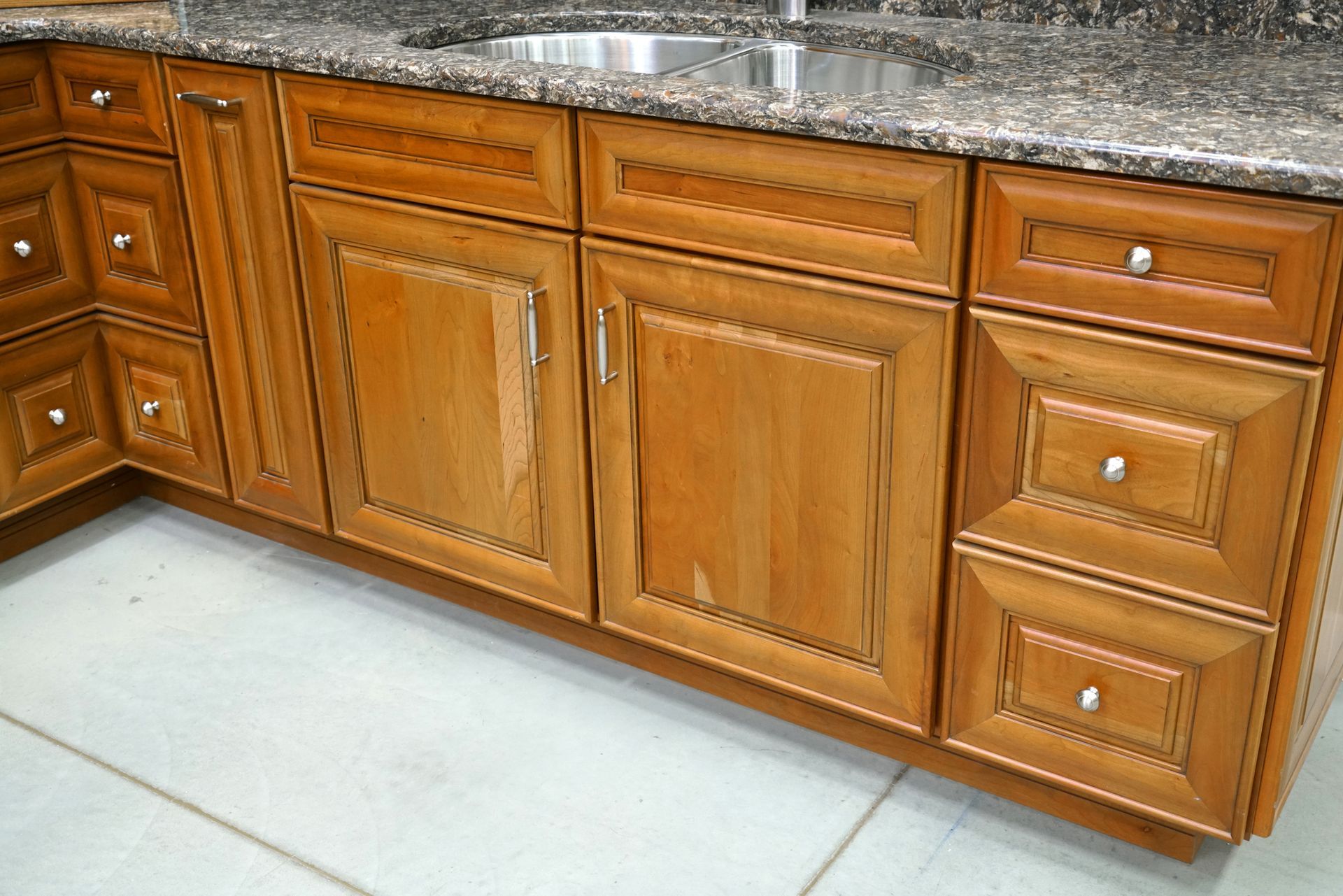 Brown wooden kitchen cabinets with granite countertop.