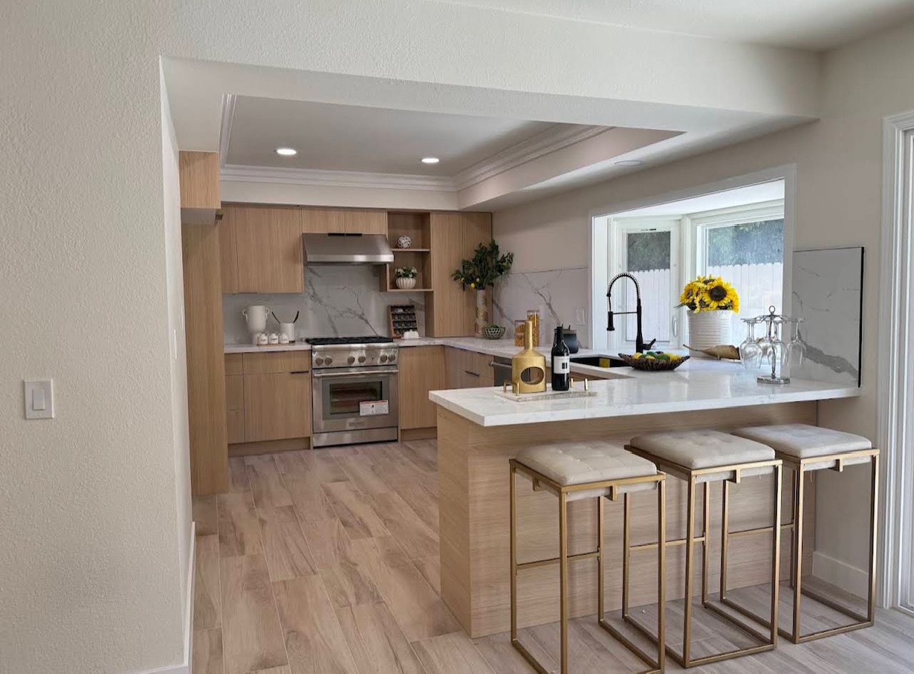 Modern kitchen with dark cabinetry, large island, wood beams, and patterned backsplash.