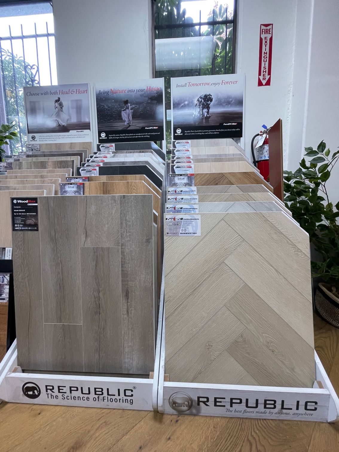 Modern living room with herringbone wood floor, mounted TV, and crystal chandelier.