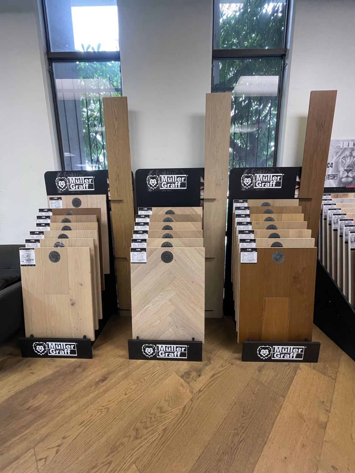 Person installing carpet tiles, with sample tiles in cardboard trays, in a room.