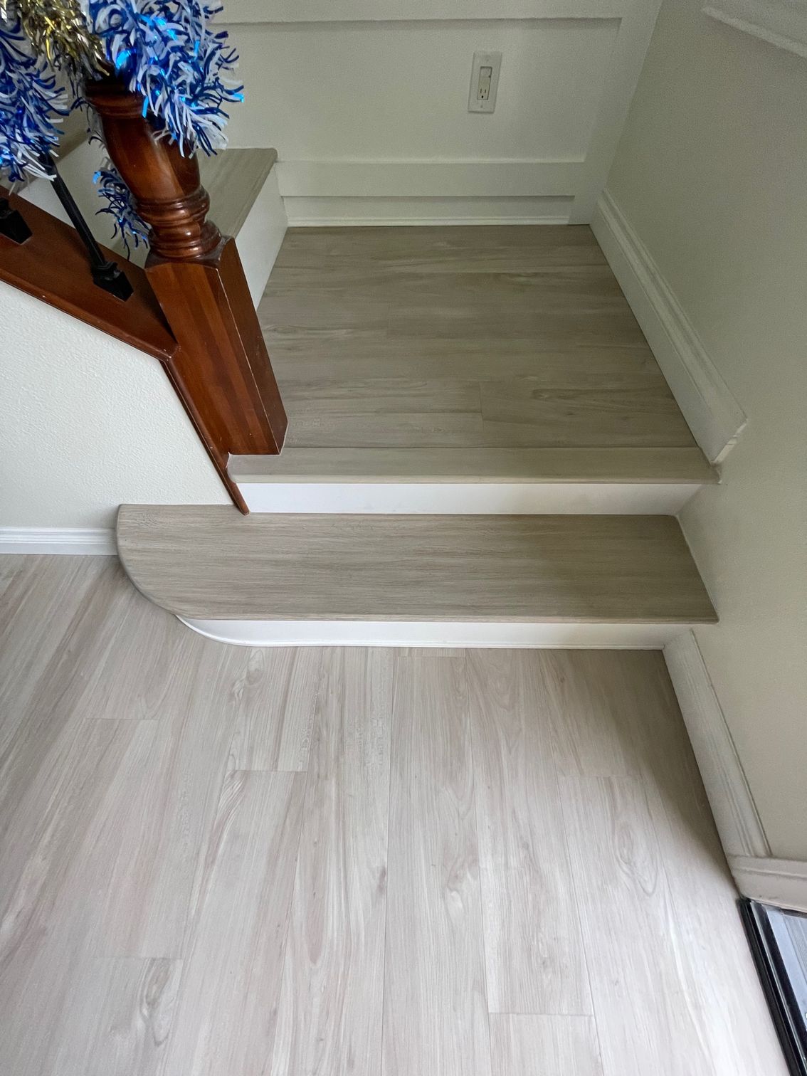 Shiny wooden floor reflecting the light from windows, with a white fireplace and tan walls.