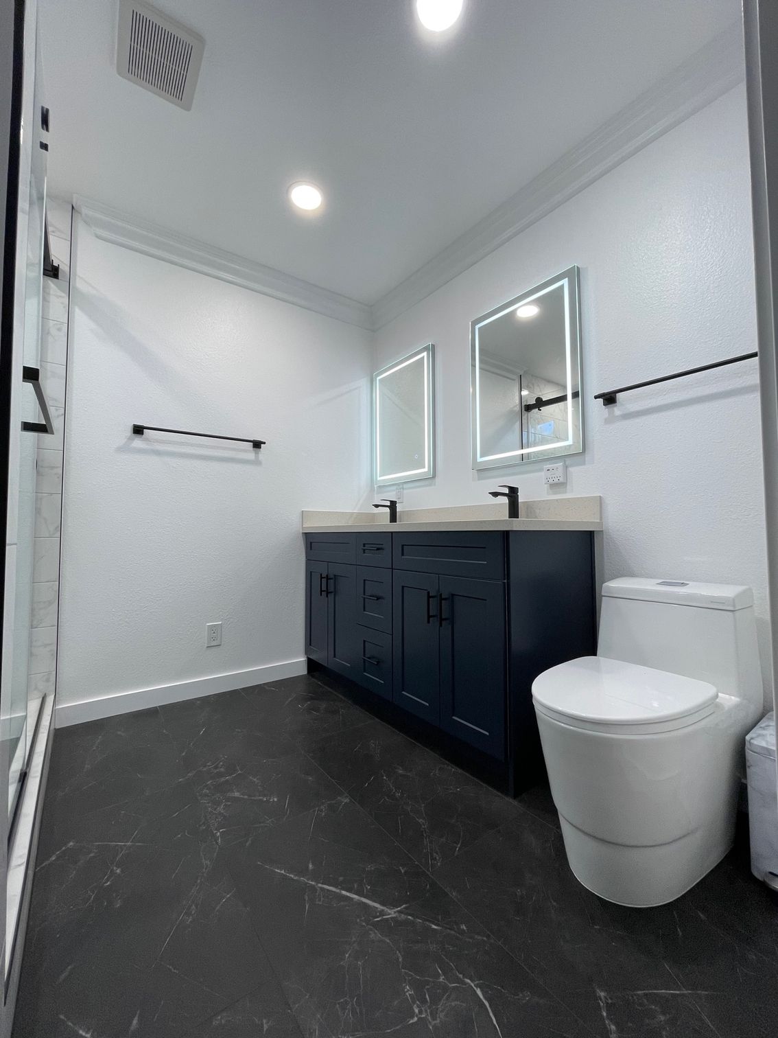 Bathroom with white tile floor, bathtub, and marble accent shelf with vase and greenery.