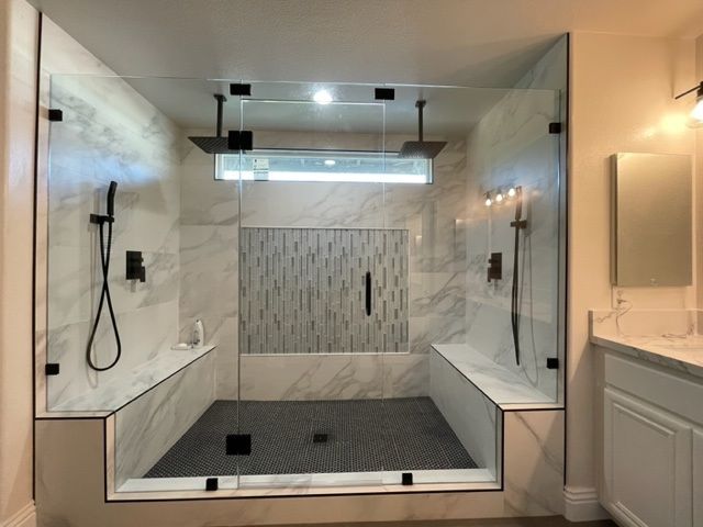 Construction worker installing wall tiles. Tools on a white table: drill, hammer, level. Grey walls, white tiles.