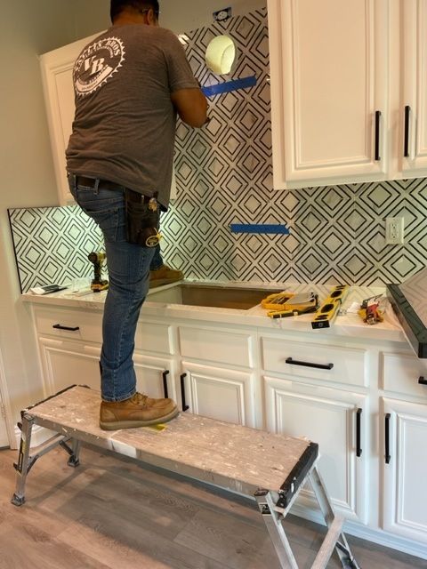 Living room with a fireplace, TV, and chandelier. Gray wood-look paneling on the fireplace wall, and dark hardwood floors.