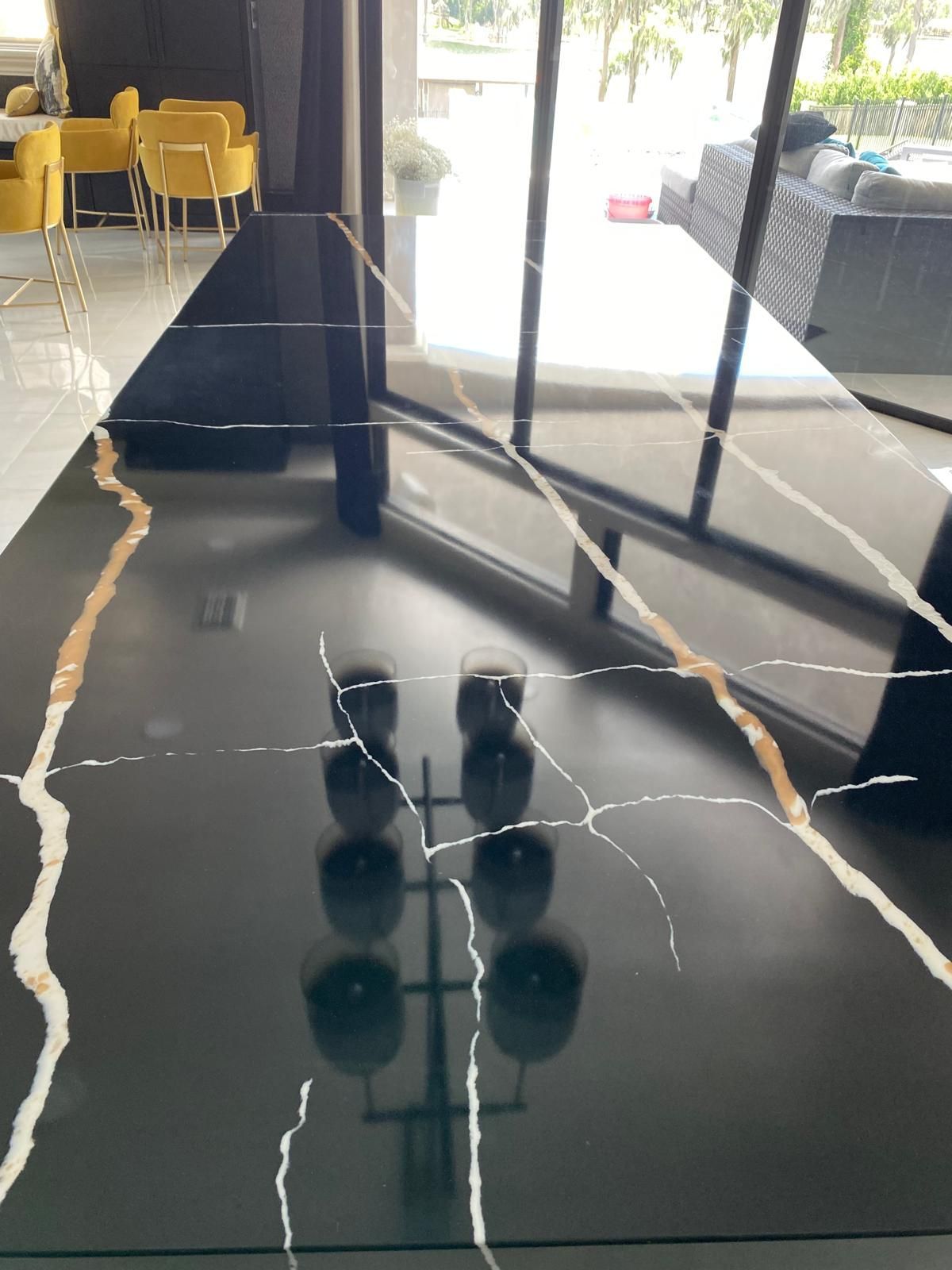 Black marble table with gold and white veining, reflecting multiple black glasses.