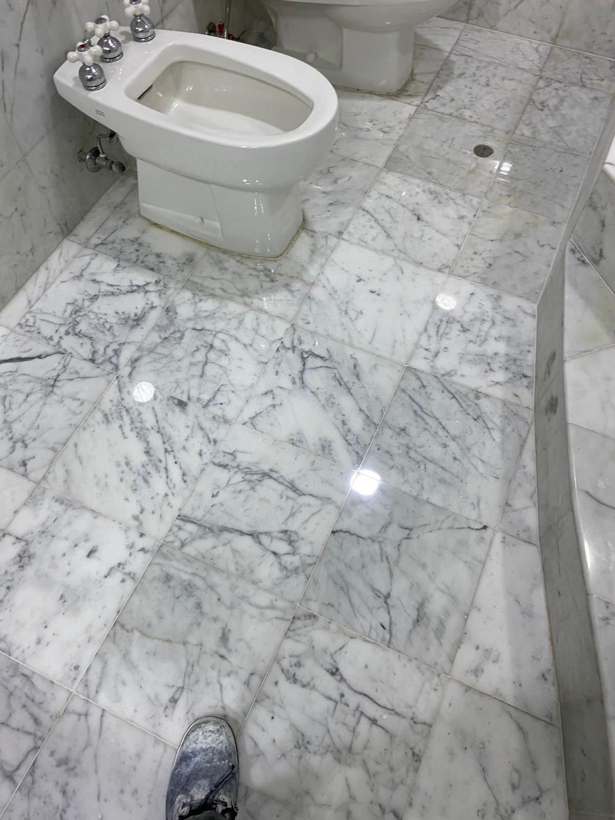 Bathroom with marble tile floor, bidet, and white toilet.