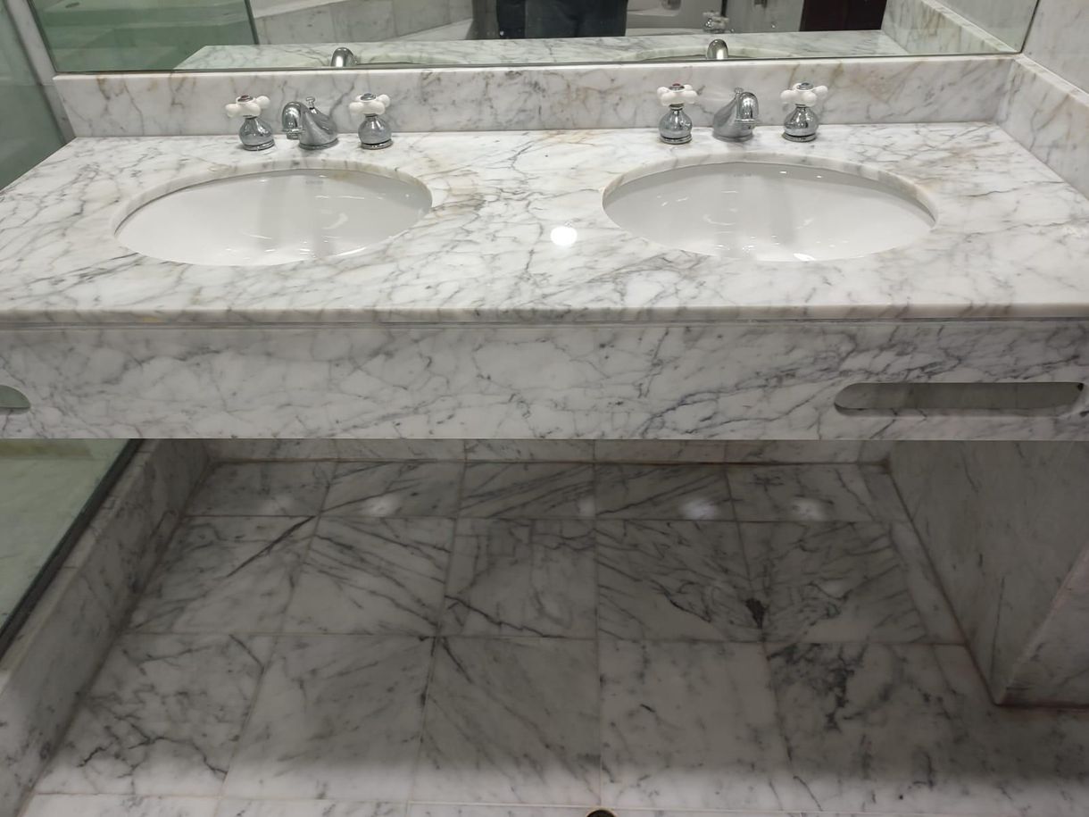 Double white marble vanity with two sinks and matching floor.