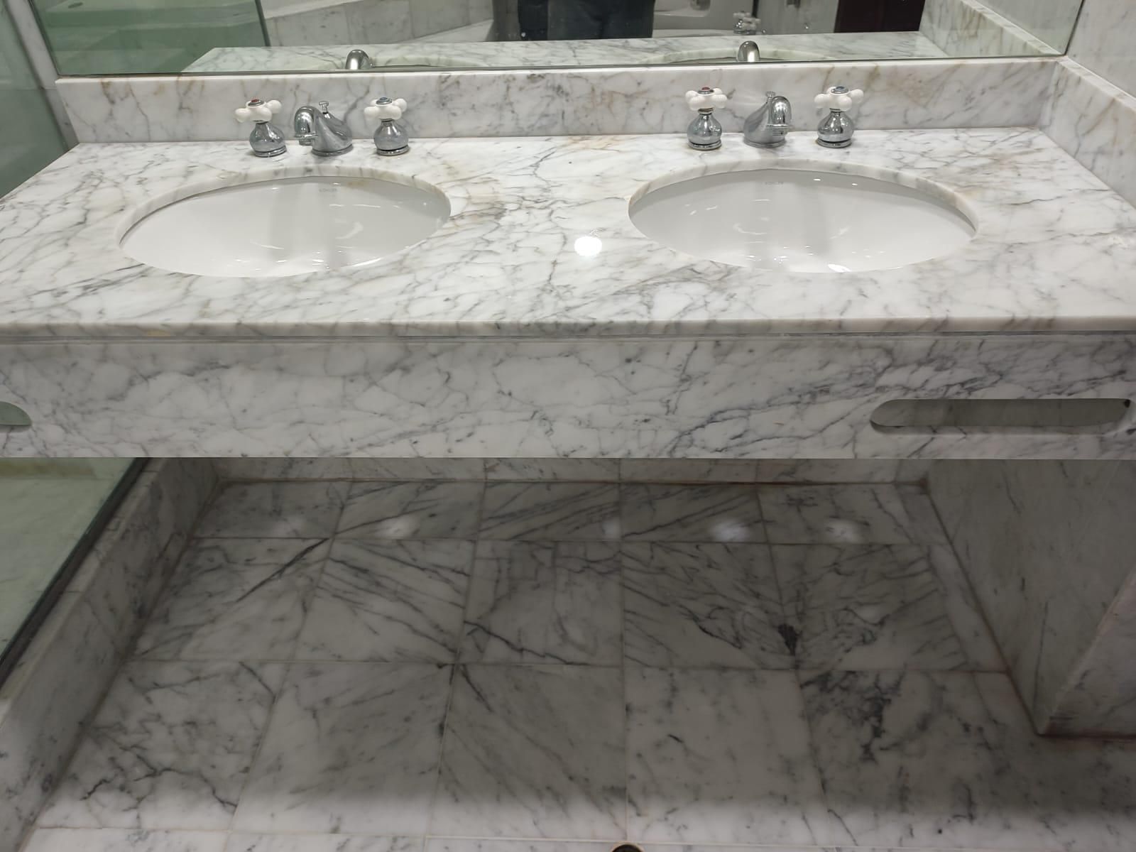 Marble double vanity with two sinks and matching tiled floor.
