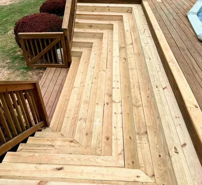 Wooden deck stairs with a zigzag design. Handrails on either side.