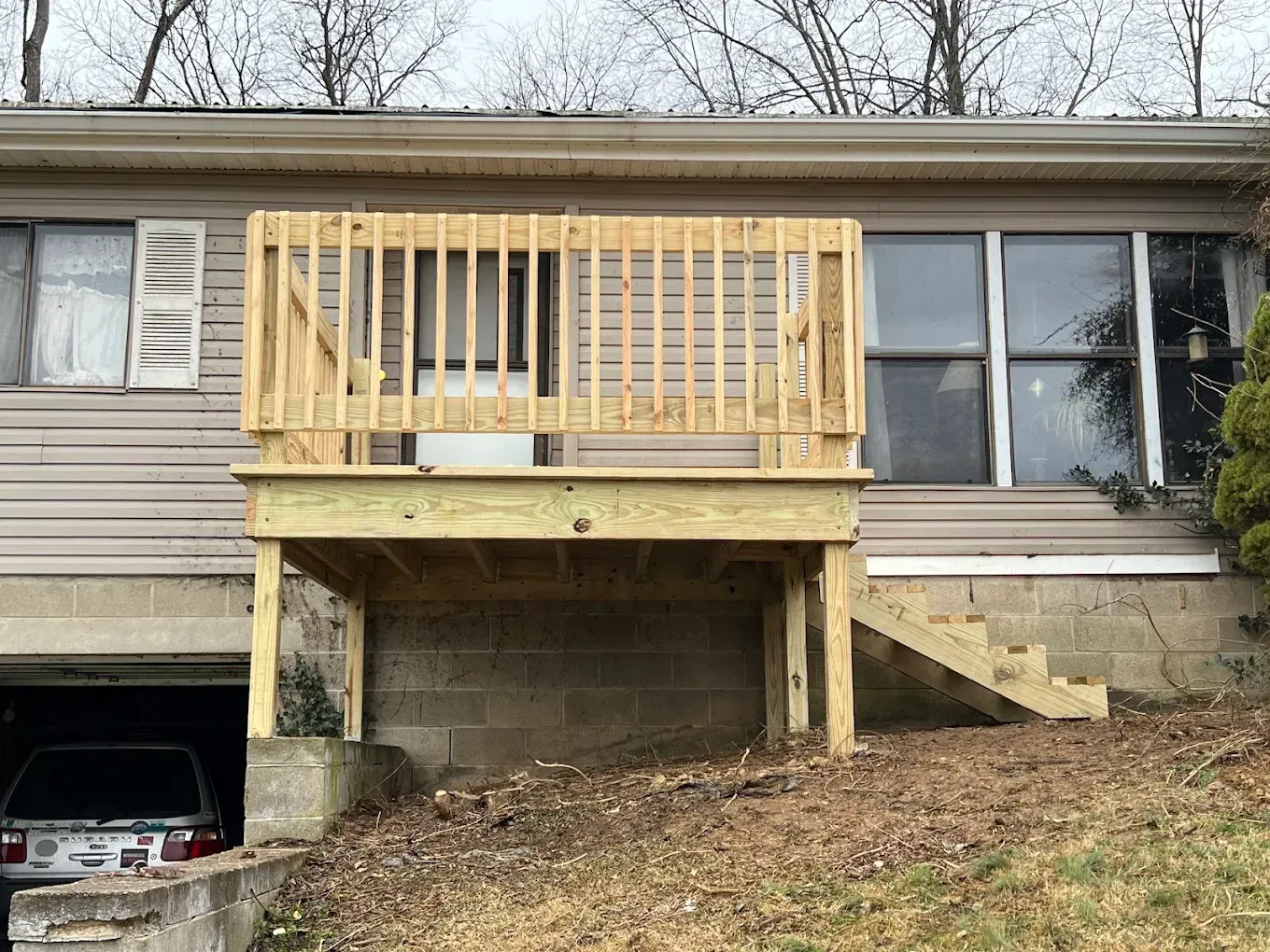 New wooden deck with stairs, built in front of a house with a garage.