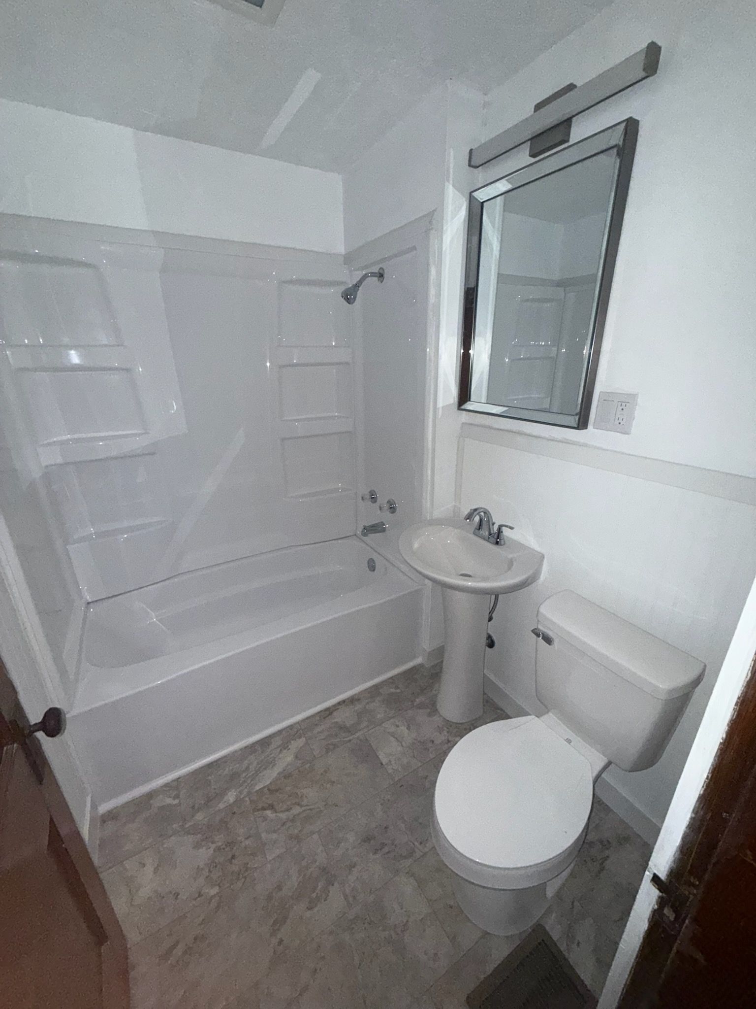 Interior of a tiny house with wood floors and ladder to a loft. Door opens to outdoor greenery.