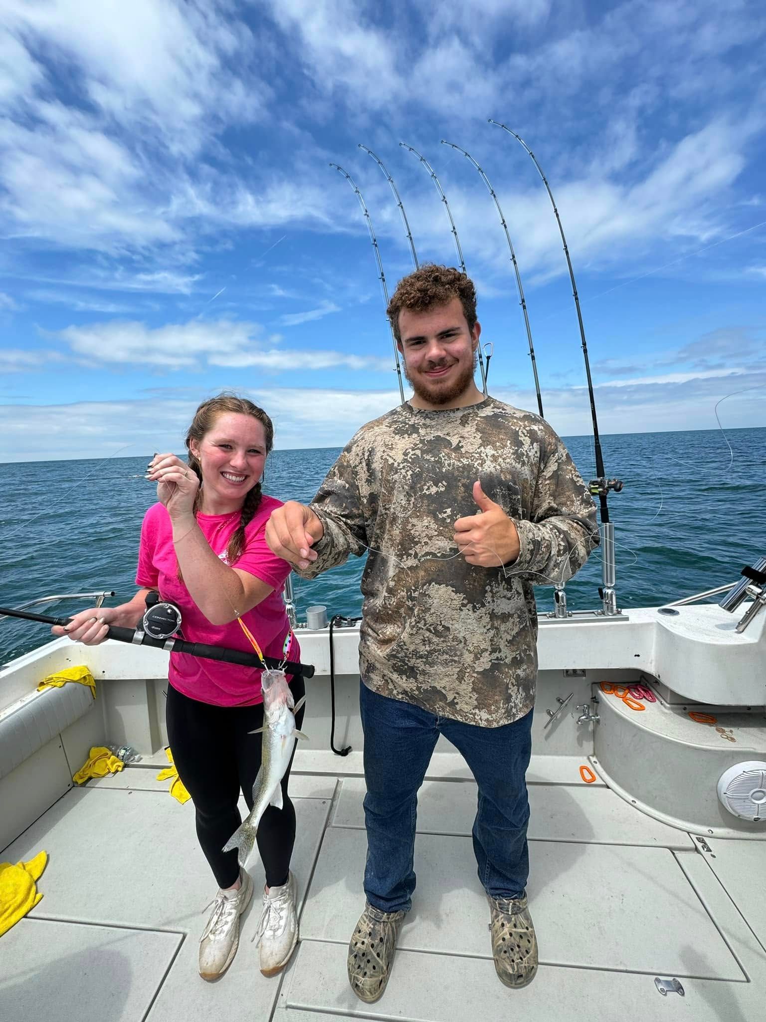 A man and a woman are standing on a boat holding fish.