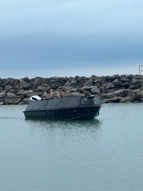 A boat is floating in the water near a rocky shoreline.