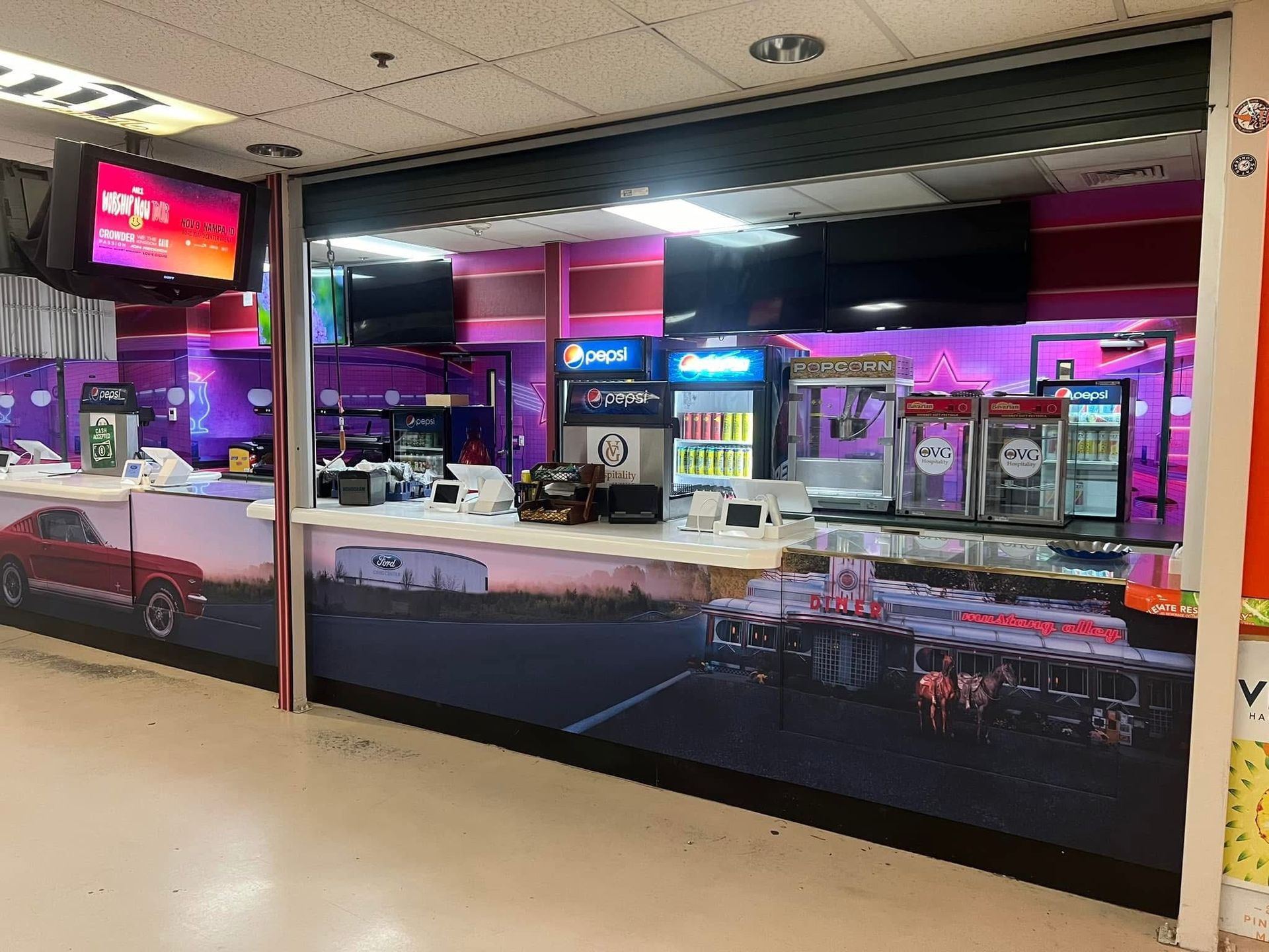 A restaurant with a pepsi machine and a picture of a car on the wall.
