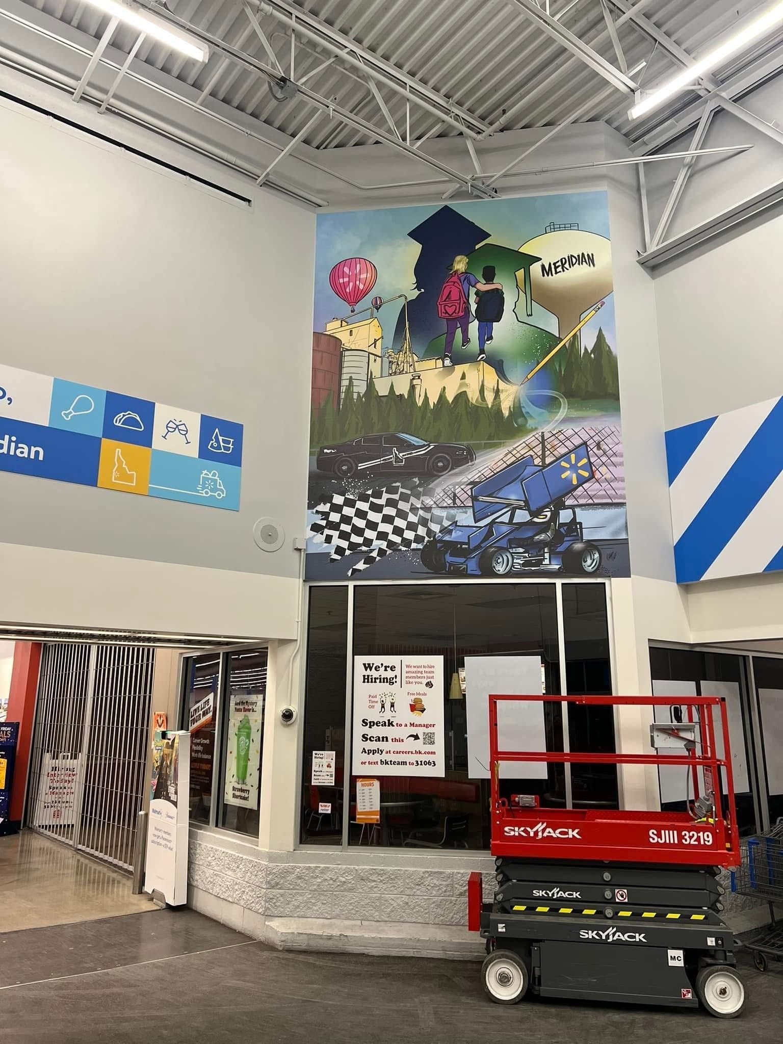 A large mural is being painted on the wall of a building.