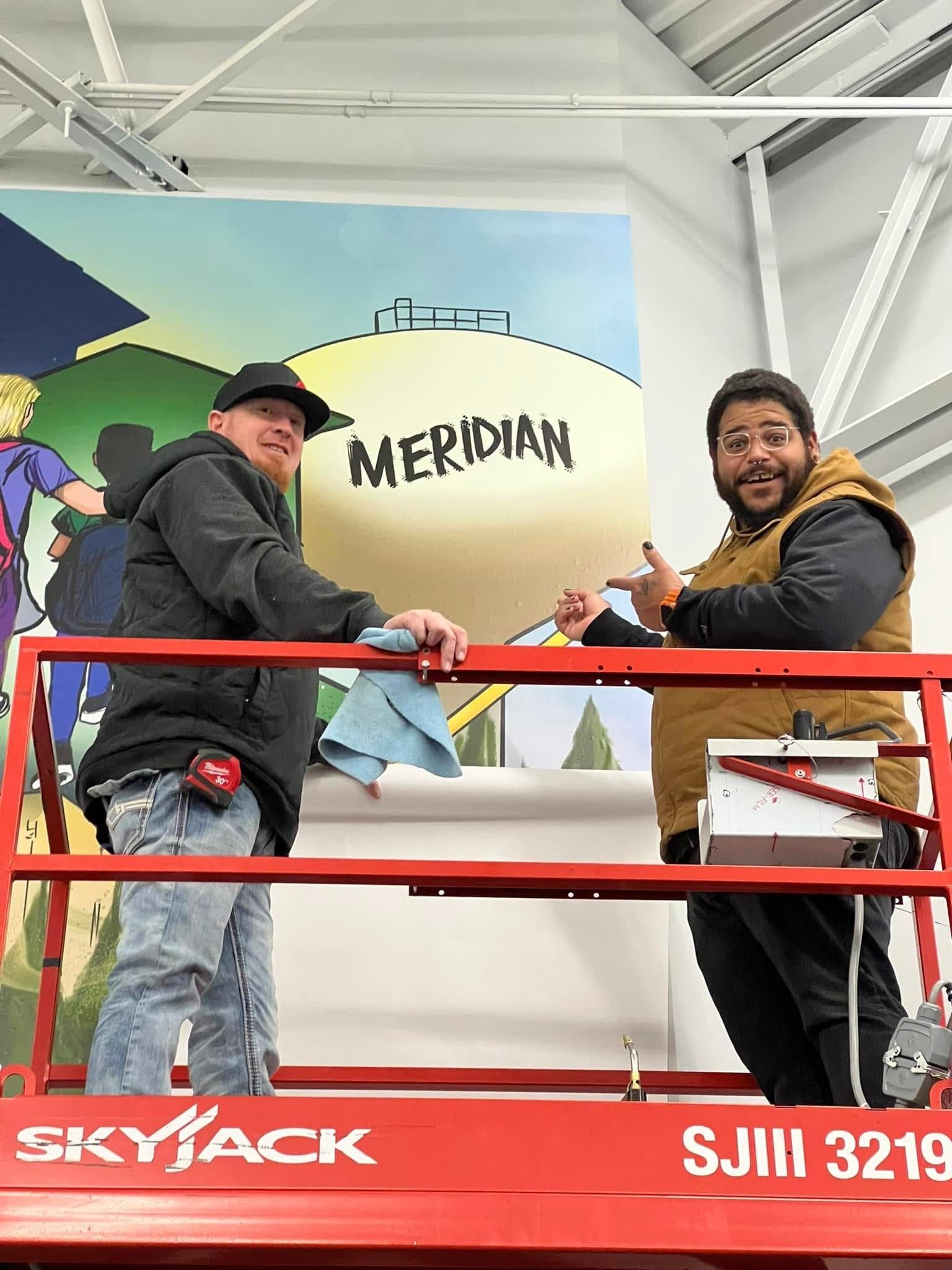 Two men are standing on top of a skyjack lift.