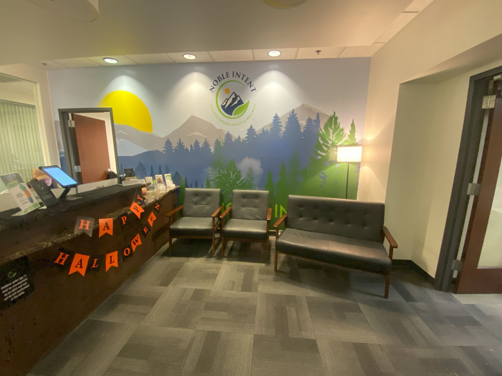 A waiting room with a couch and chairs and a mural on the wall.