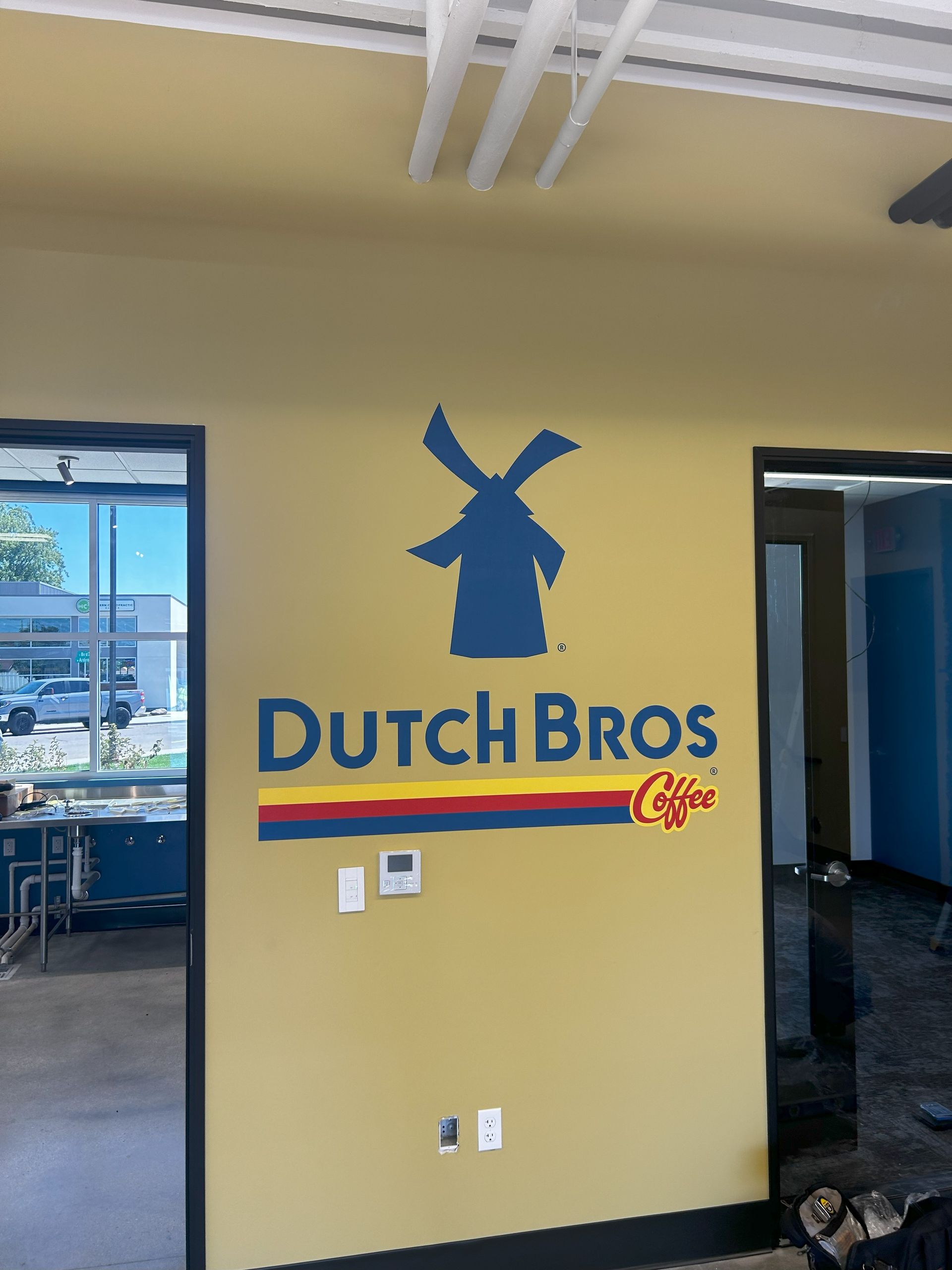 A yellow wall with a dutch bros logo on it