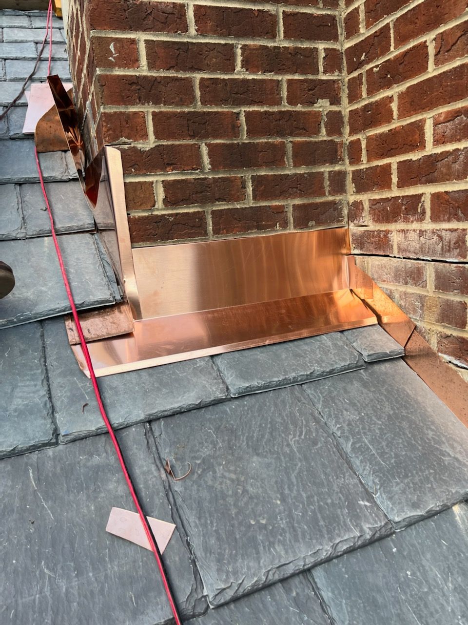 a copper gutter is being installed on the roof of a brick building .