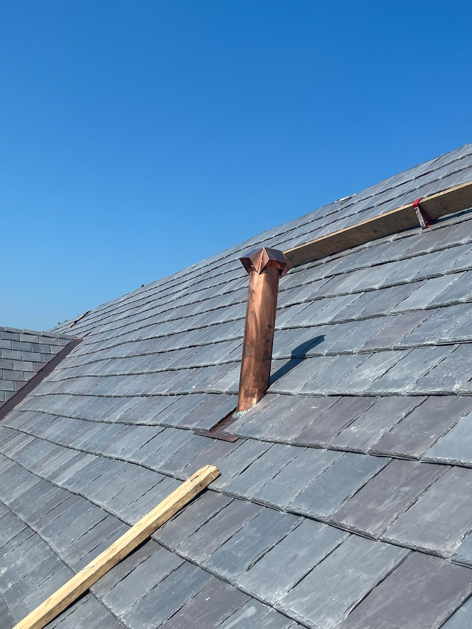 a copper pipe is sitting on top of a slate roof .