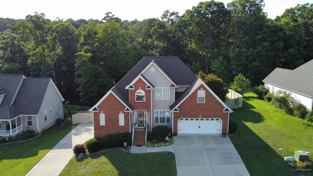 an aerial view of a large brick house in a residential neighborhood