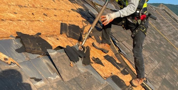 a man is standing on top of a roof with a shovel .