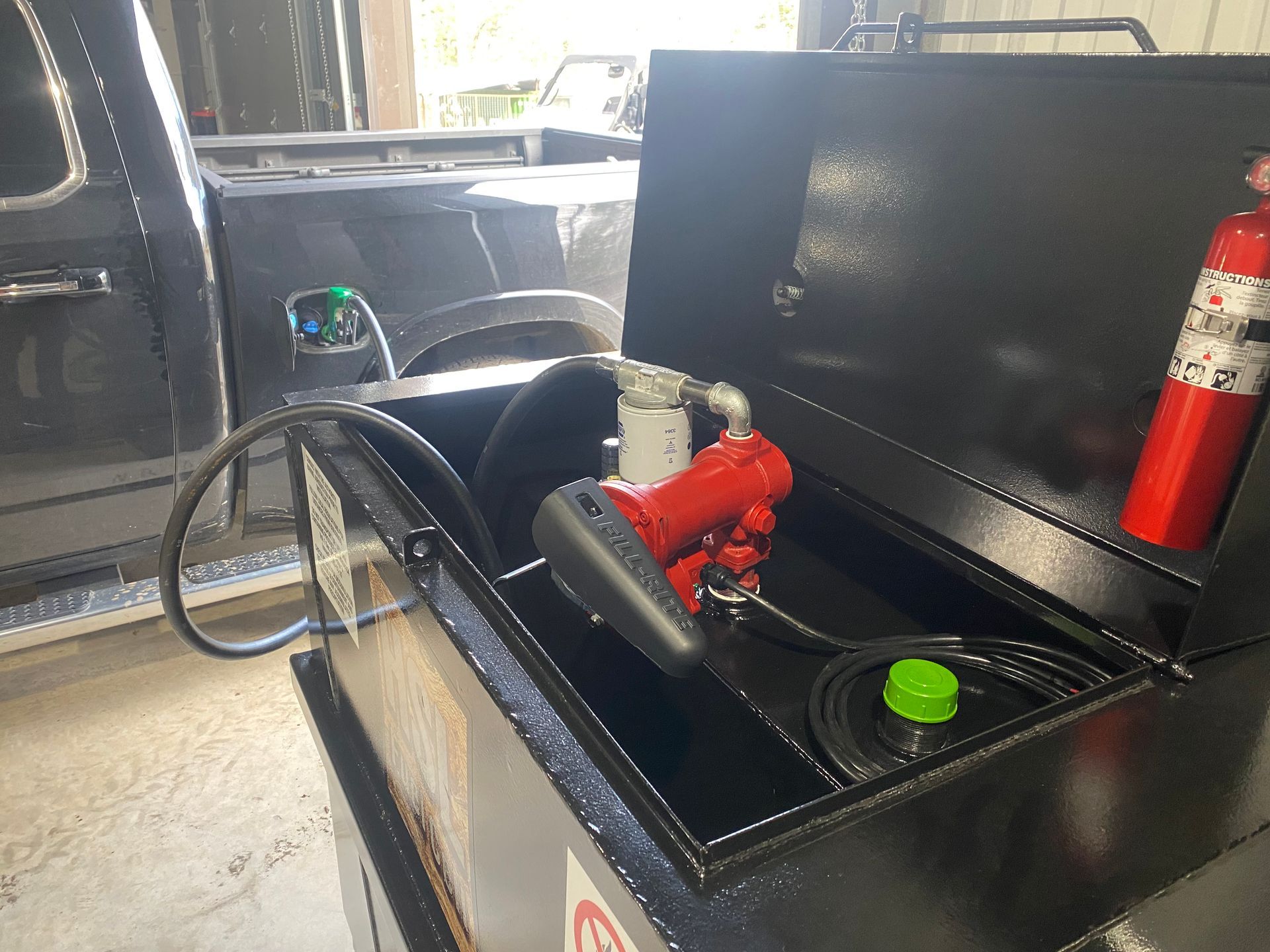 A fire extinguisher is sitting on top of a fuel tank next to a truck.