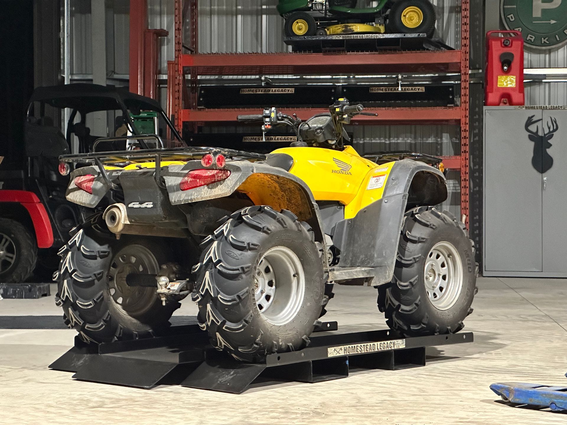 A yellow atv is parked on a ramp in a garage.