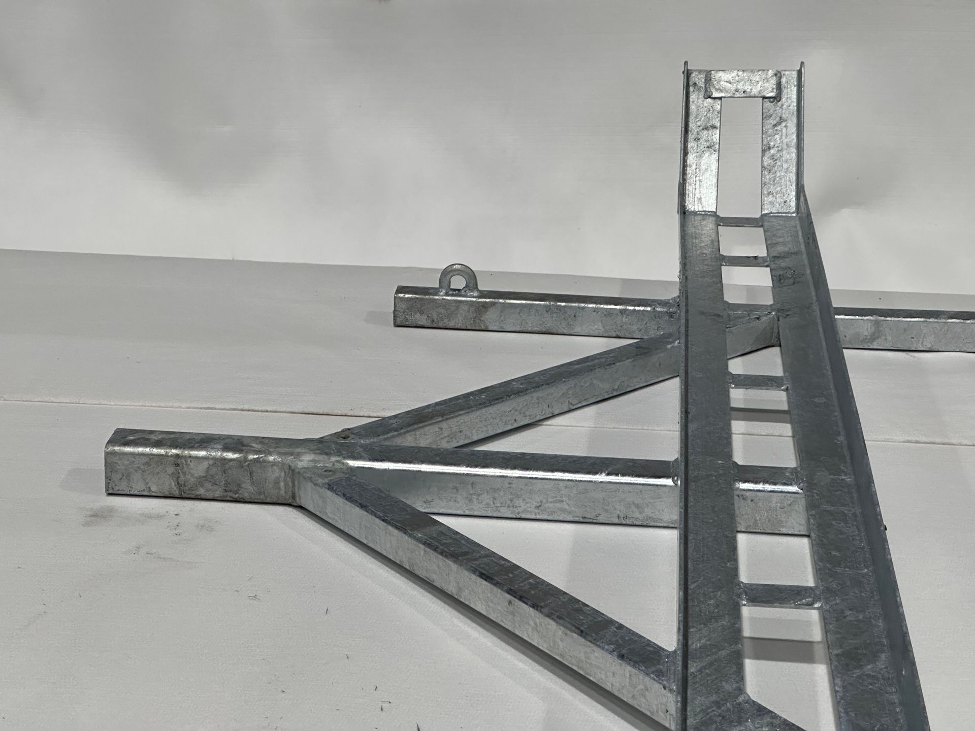 A metal triangle with a hole in the middle sits on a white surface