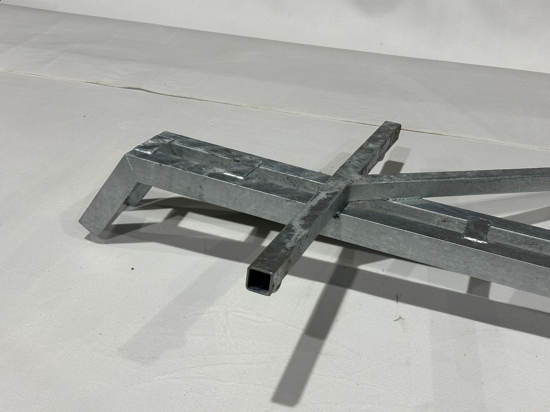 A metal cross is laying on a white surface.