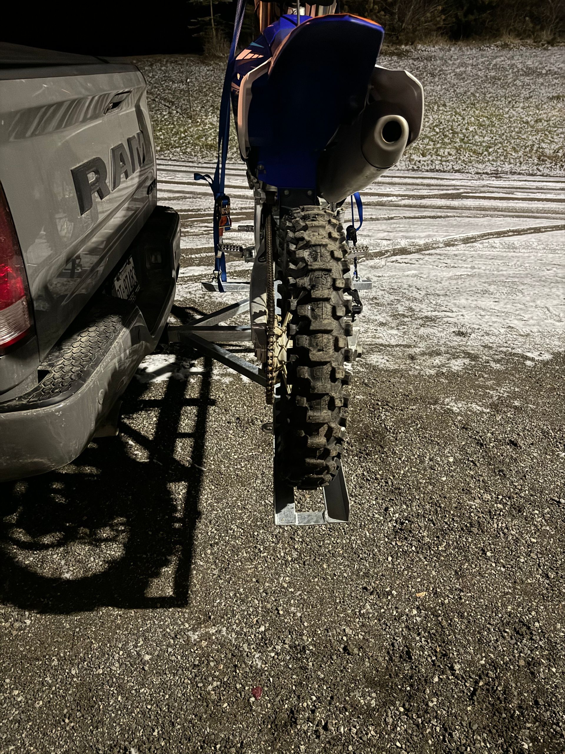 A dirt bike is attached to the back of a truck.