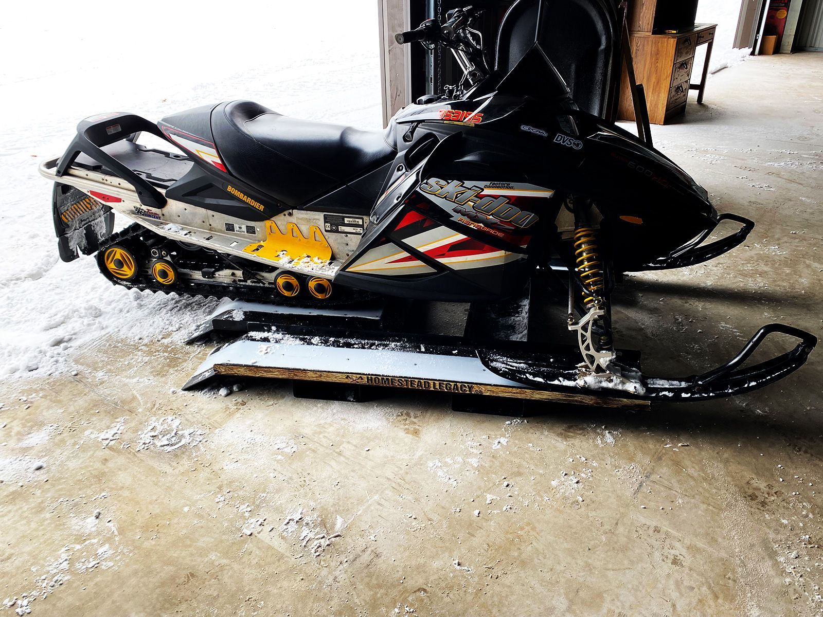 A black and yellow snowmobile on a homestead legacy sled bed