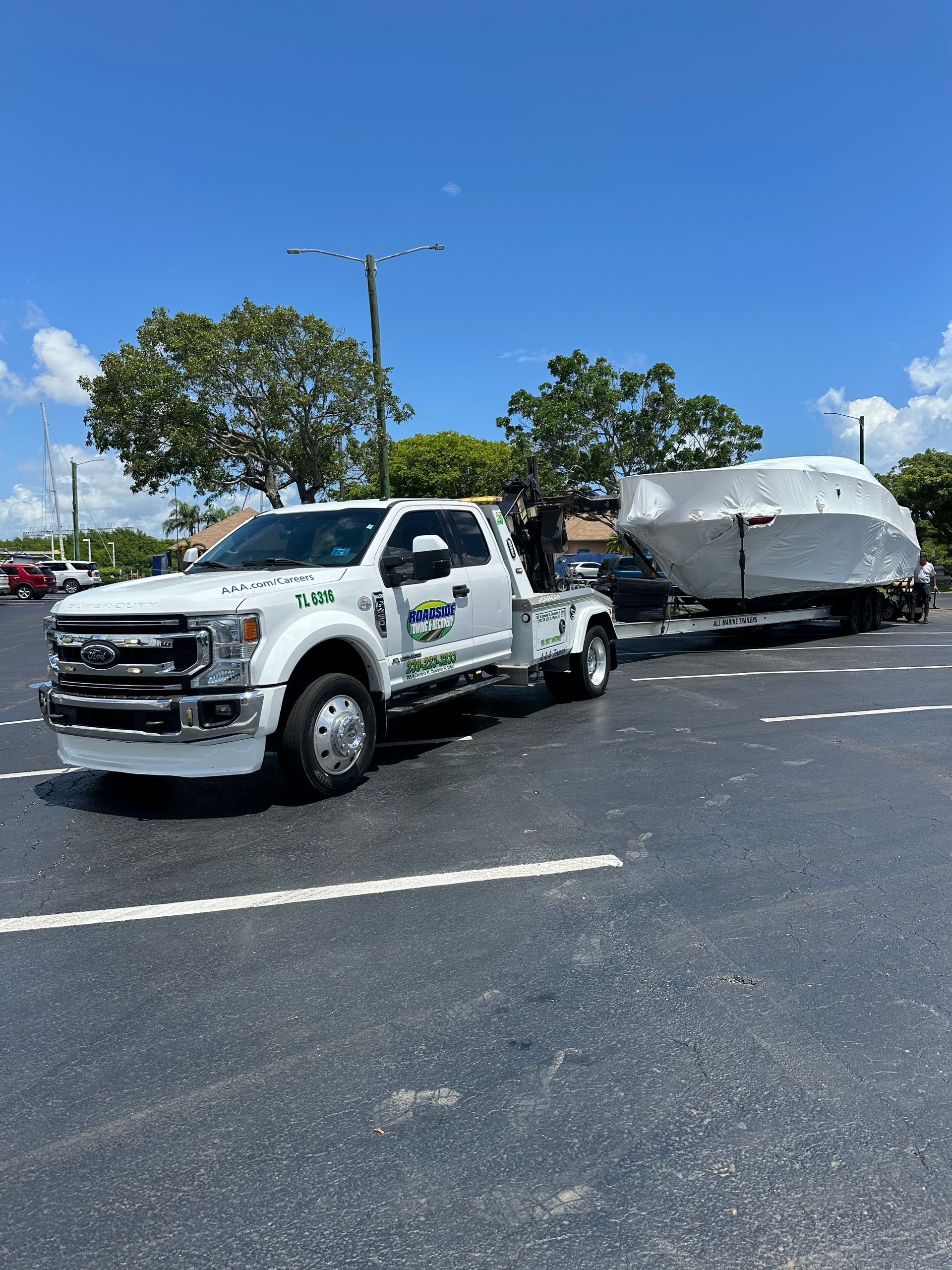 Boat hauling service in Miami – covered boat transport with flatbed trailer and tow truck for marina delivery