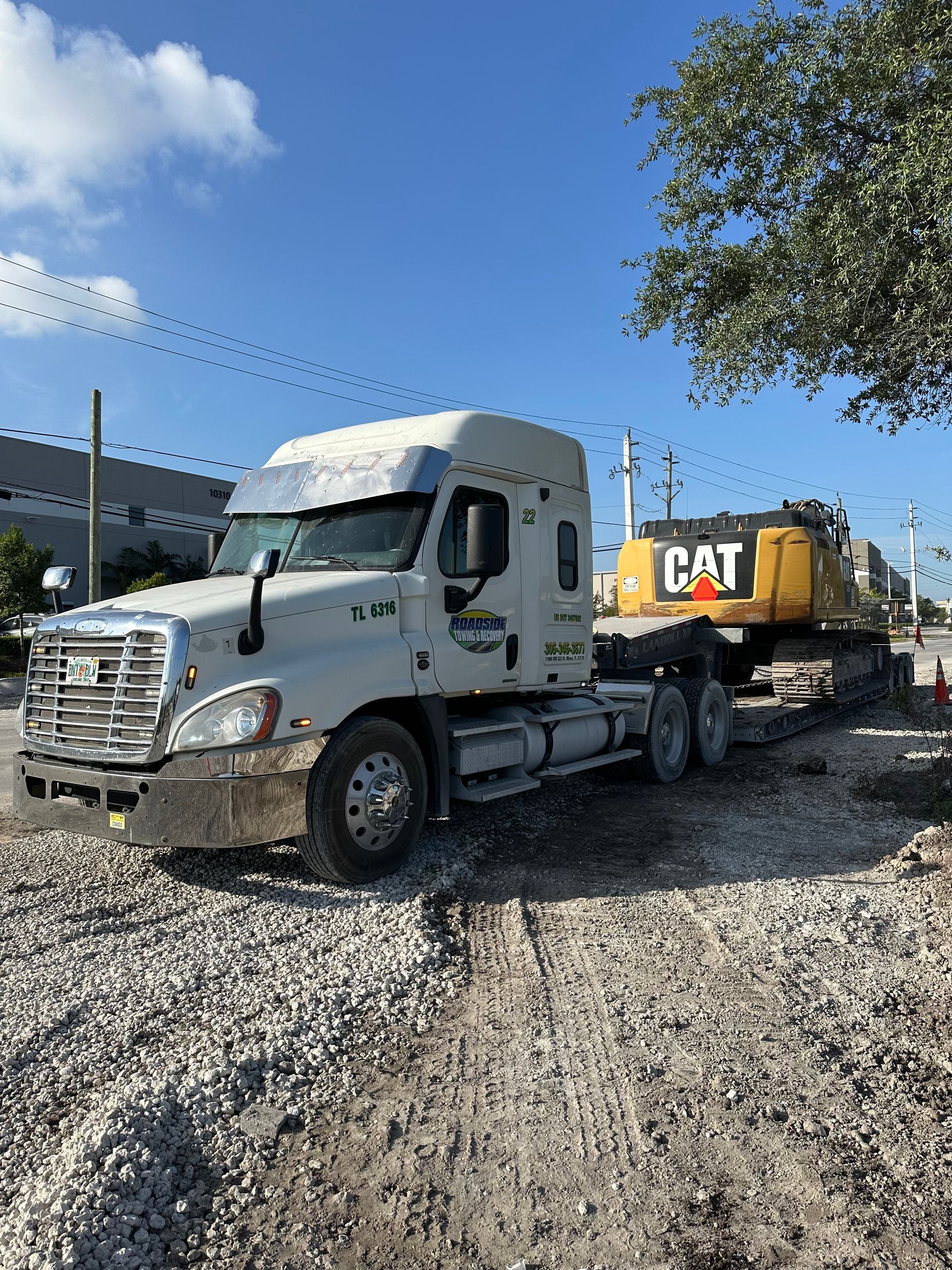 CAT excavator transport in Miami – heavy equipment hauling service with semi-truck and lowboy trailer for construction projects.