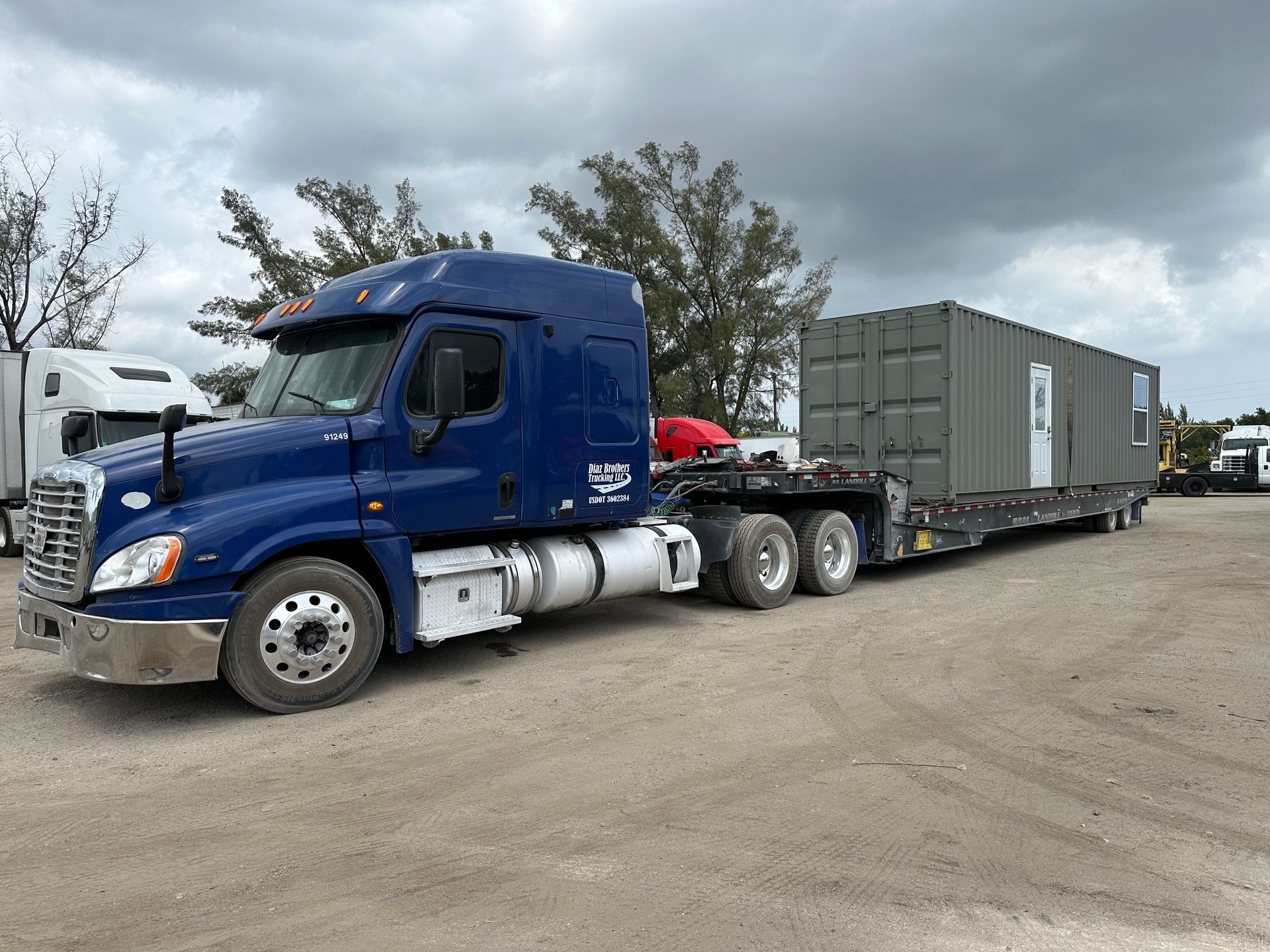 Container home transport in Miami – heavy-duty semi-truck hauling modular building on flatbed trailer