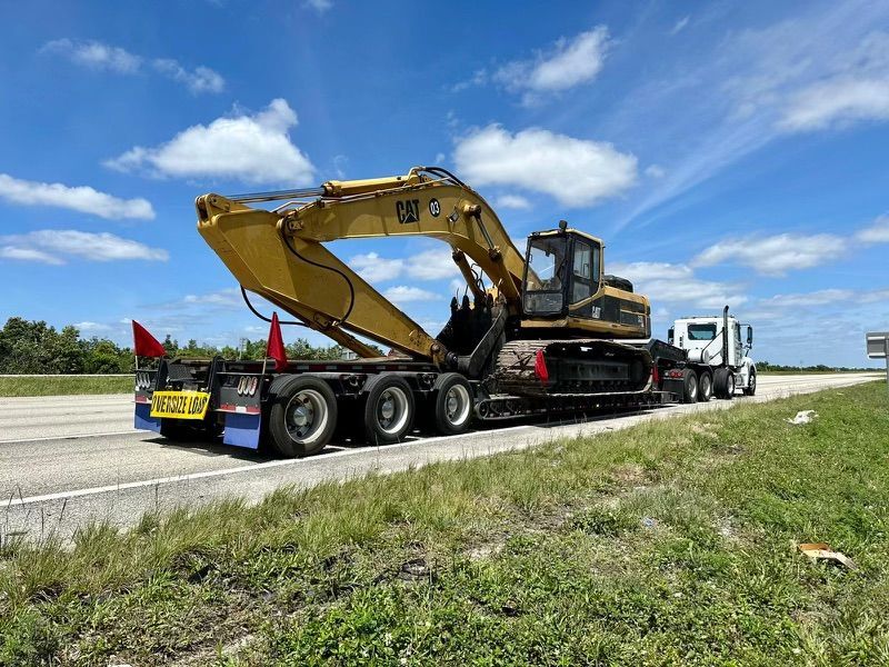 Heavy equipment hauling Miami – CAT excavator transport on lowboy trailer for oversized load delivery