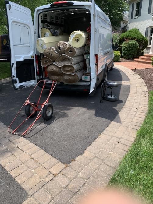 Worker using a cutter to carefully install new carpet flooring in a room, ensuring precise measurements and smooth placement.