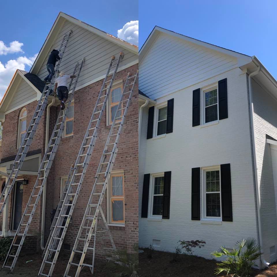 A white house with black shutters is being painted
