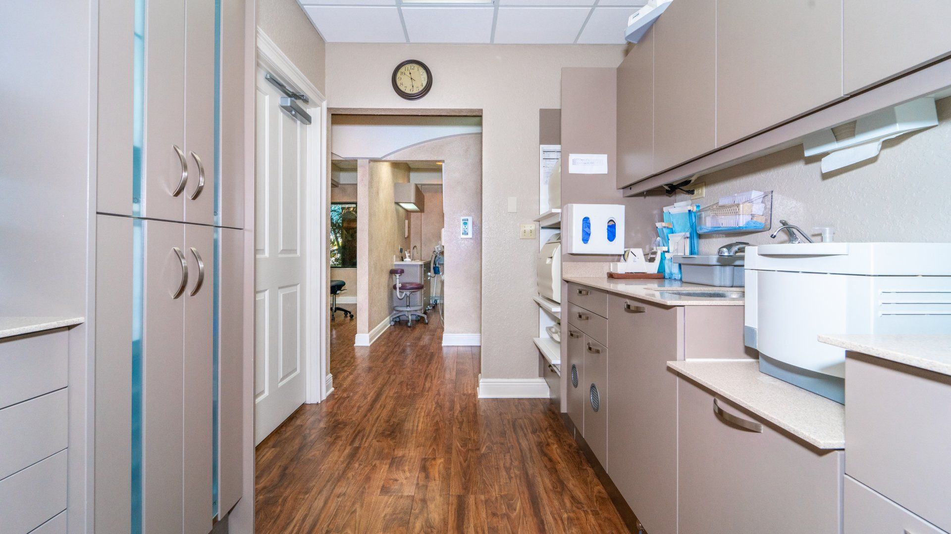 A hallway in a dental office with wooden floors and cabinets.