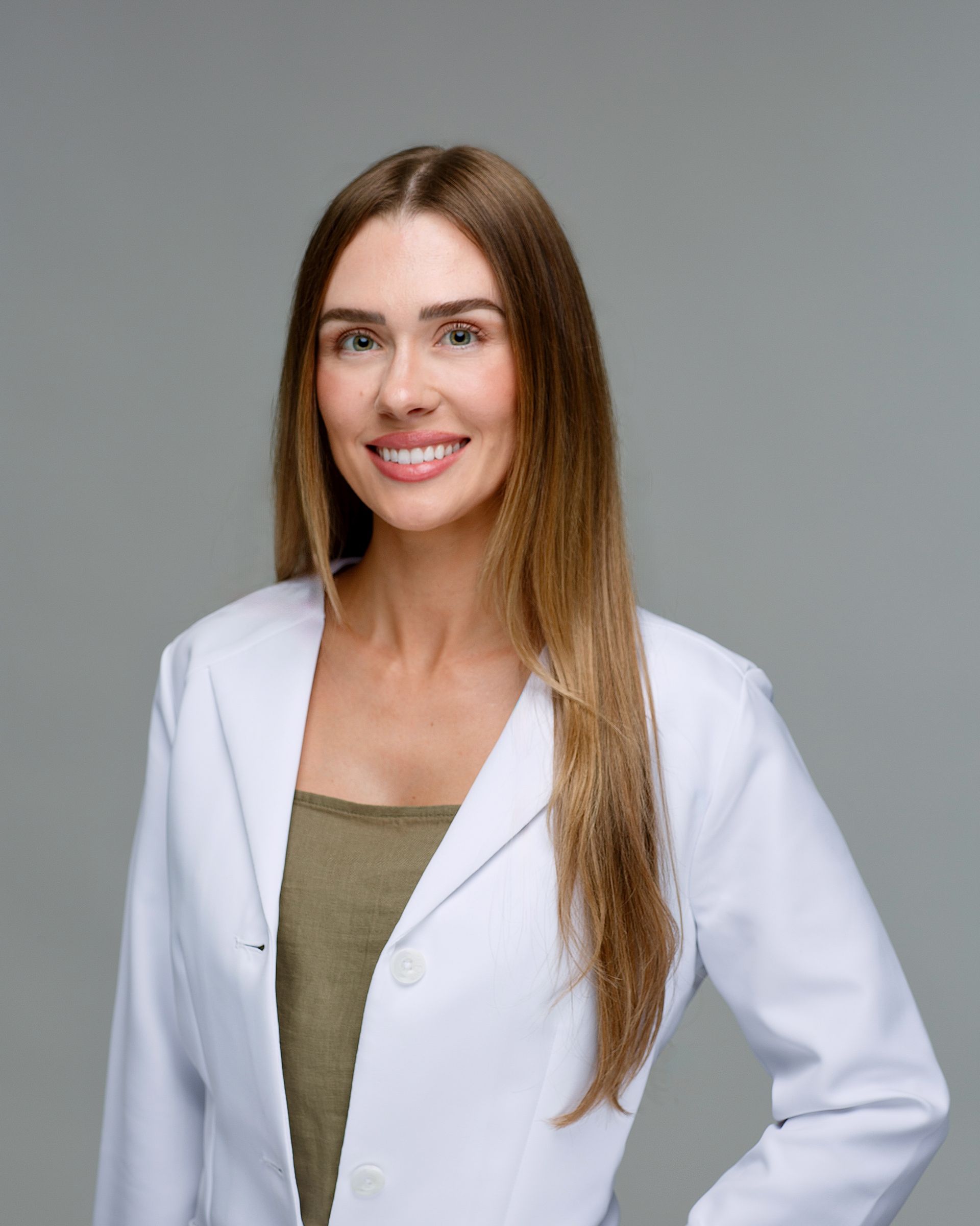 A man in a lab coat and tie is smiling for the camera.