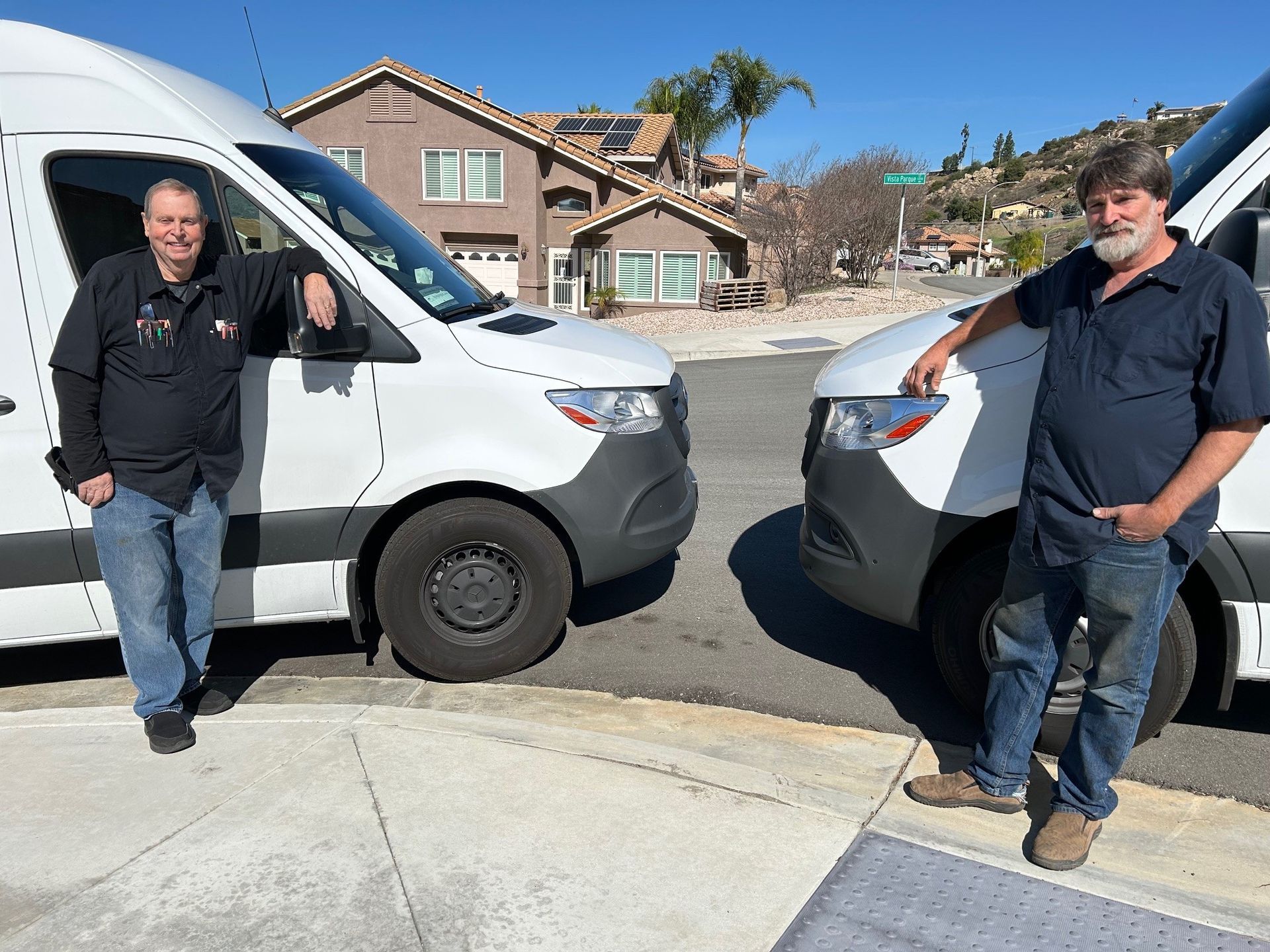 Two men stand beside a white van Two men stand beside a white van