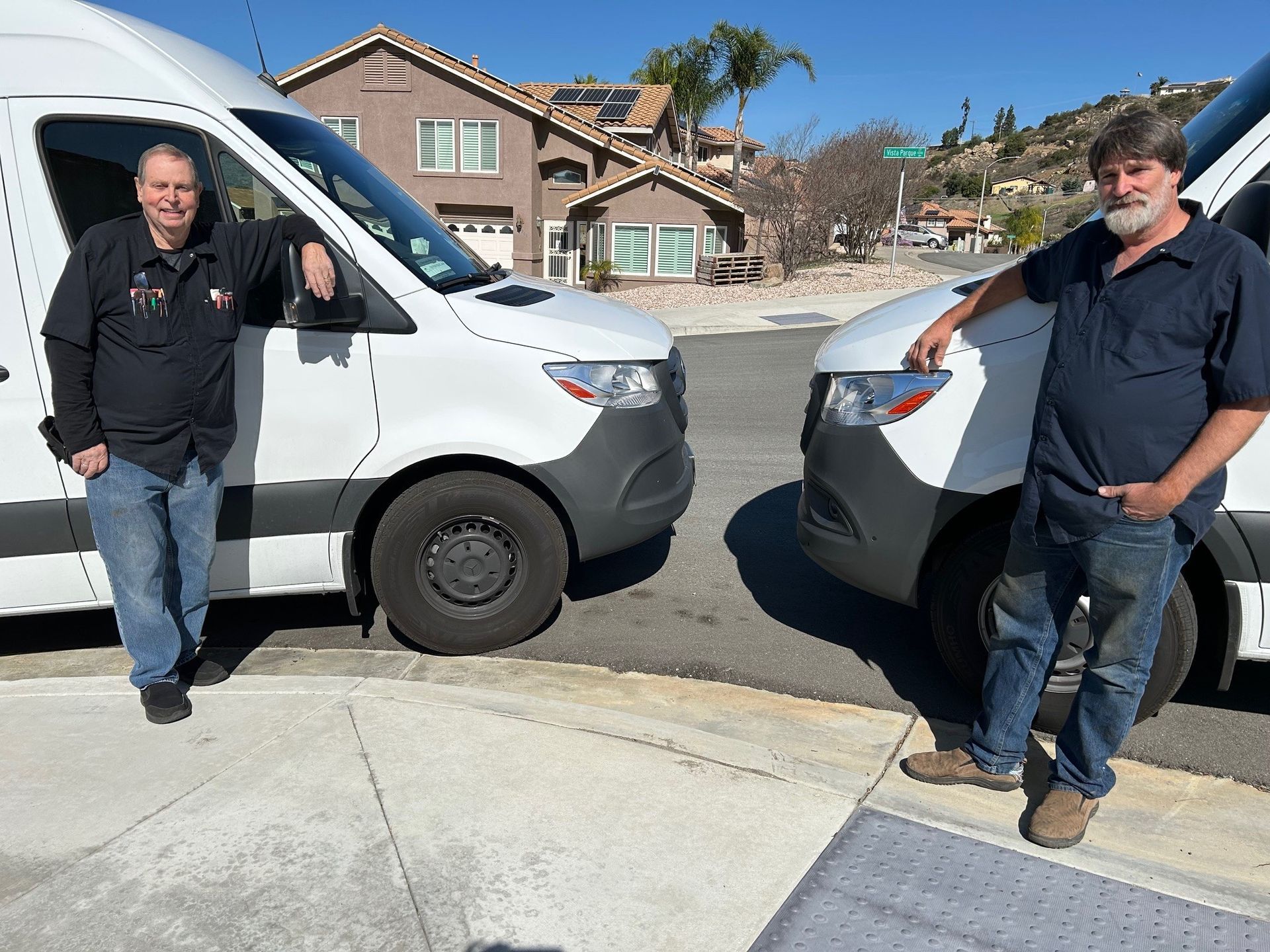 Two men are standing in front of two white vans Two men are standing in front of two white vans