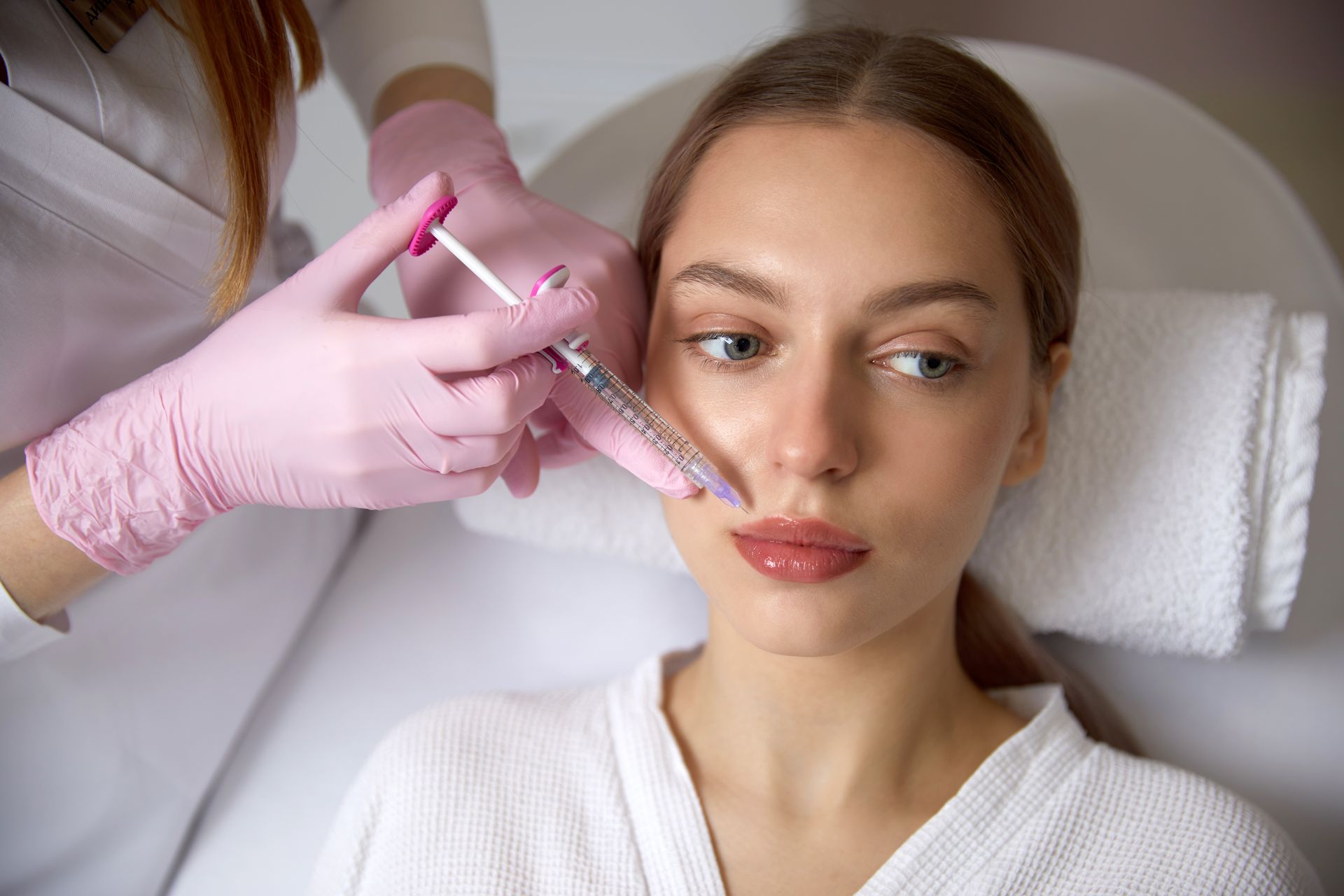Cosmetic treatment with a syringe injected into a woman’s cheek in a spa setting